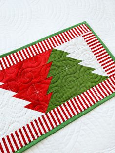 a close up of a quilted christmas tree on a table top with red and white stripes