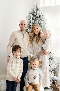 a family posing for a photo in front of a christmas tree with their two children