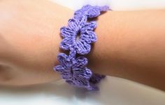 a close up of a person's arm wearing a purple crochet bracelet