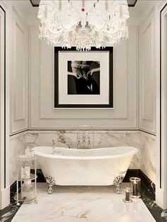 a white bath tub sitting in a bathroom next to a chandelier above it