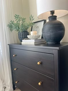 a black dresser with two vases and a lamp on top