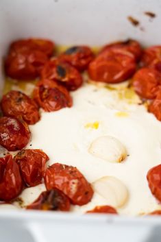 tomatoes and garlic are mixed together in a white dish with yogurt on top