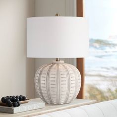 a white lamp sitting on top of a table next to a book and some grapes