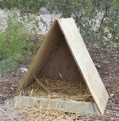 a wooden structure sitting in the middle of some dry grass and straw on the ground