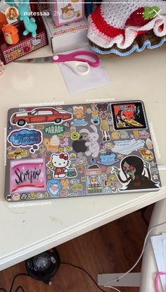 a laptop computer sitting on top of a desk covered in stickers and magnets