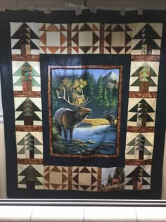 a quilted wall hanging with an image of a moose in the woods on it