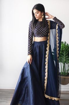 a woman in a blue lehenga with gold trimmings and a black crop top