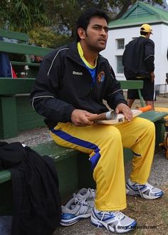 a man sitting on a bench in front of a baseball bat and catchers mitt