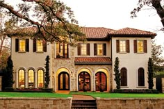 a large white house with lots of windows on it's sides and trees in the front yard