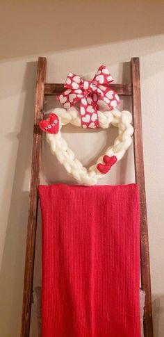 a red towel hanging on a ladder with a heart shaped decoration attached to it's side