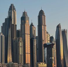 a large group of tall buildings in the middle of a body of water with boats on it