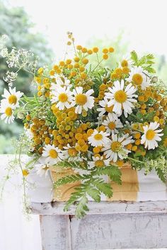 a vase filled with lots of yellow and white flowers