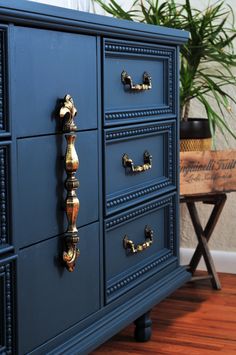 a blue dresser with brass pulls and knobs on it's drawers in a living room