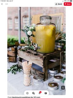 a table topped with lots of mason jars filled with yellow liquid and flowers on top of it