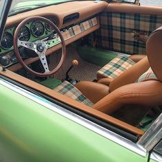 the interior of a green car with plaid upholstered seats and steering wheel covers