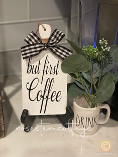 a sign that says but first coffee next to a cup with a plant in it