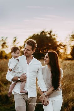 a man, woman and child walking through a field