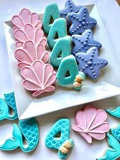 decorated cookies are arranged on a plate next to other cookie decorating items, including letters and seashells