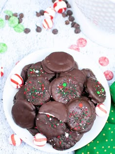 a plate full of chocolate covered cookies on a table with candy canes around it