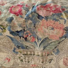 an old floral fabric with pink and blue flowers on the top, sitting on a wooden table