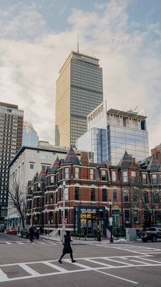 a person walking across a street in front of tall buildings