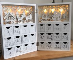 two white wooden calendars sitting on top of a table next to each other with paper cut outs