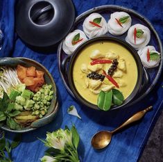 there are many different foods in bowls next to each other on the blue table cloth