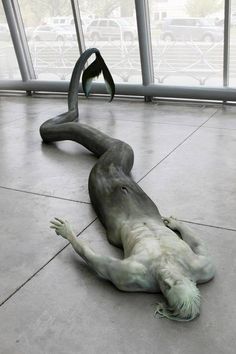 a statue is laying on the ground with its legs spread out