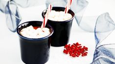 two cups filled with hot chocolate and marshmallows on top of a table