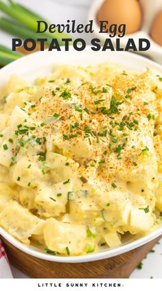 an egg potato salad in a white bowl with green onions and parsley on the side