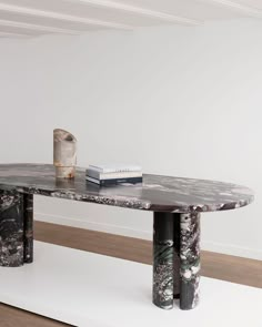 the table is made out of marble and has two black pillars on each end, along with books