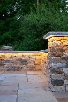 a stone wall with lights on it and some trees in the backgroung