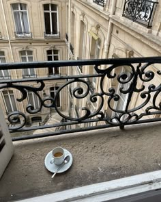 a cup of coffee is sitting on the balcony overlooking an apartment building with balconies