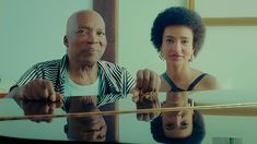 a man and woman sitting at a table with their reflection in the glass on it