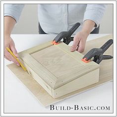 a woman is using pliers to cut the wood for a cabinet door with two screwdrivers