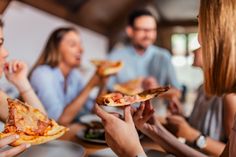 group of people eating pizza in a restaurant