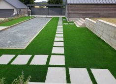 a backyard with grass and stepping stones in the center, surrounded by landscaping materials that are laid on top of concrete blocks