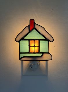 a light that is on the wall with a house shaped lamp in front of it