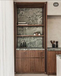 a kitchen with marble counter tops and wooden cabinets in the back wall, along with white columns