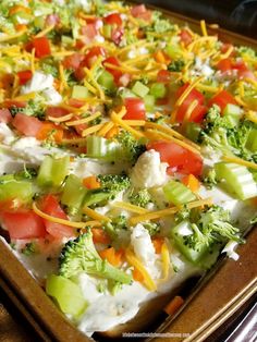 a casserole dish with broccoli, tomatoes, cheese and other toppings