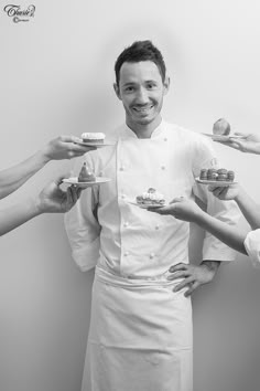 three chefs are holding plates with pastries on them, and one man is smiling at the camera