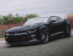 a black chevrolet camaro is parked on the street