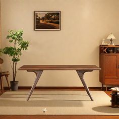 a room with a table, chair and potted plant on the floor in front of it