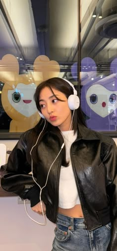 a woman wearing headphones standing in front of a teddy bear wallpapered window