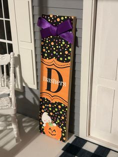 a door hanger decorated with an orange and black pumpkin, polka dot pattern and the letter d