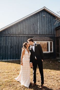 a bride and groom kissing in front of a barn