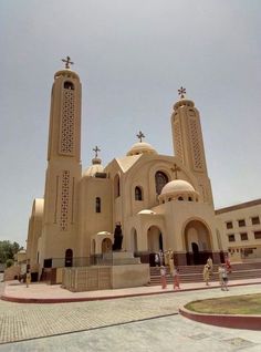 the large church has two towers and crosses on it's sides, with people walking around