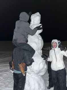 two people standing next to a snow man