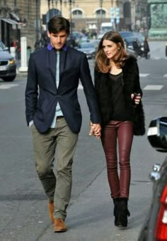 a man and woman walking down the street holding hands