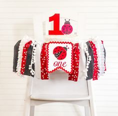 a white chair with a red and black ladybug 1st birthday banner on it